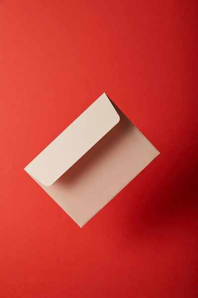 beige, blank and empty envelope on red background with copy space 
