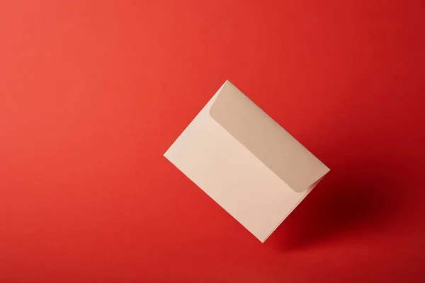 コピー スペースでカラフルな赤の背景にベージュ 空の封筒 — ストック写真