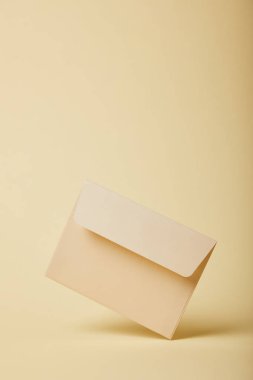 beige and empty envelope on yellow background with copy space  clipart