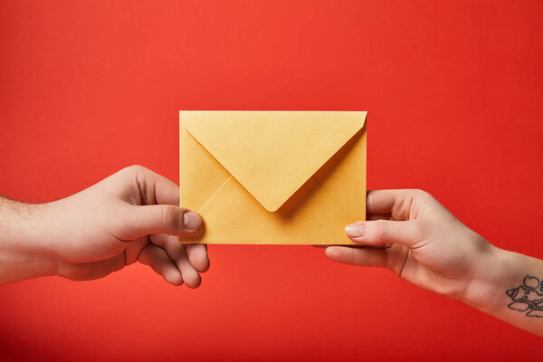 partial view of woman with tattoo and man holding yellow envelope on red background 