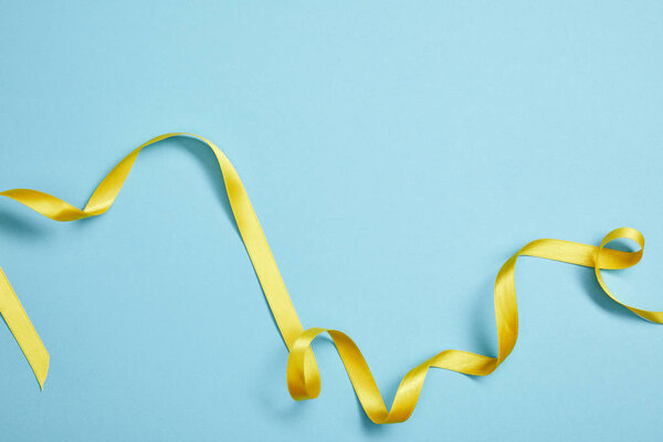 вид сверху на желтую атласную ленту на голубом фоне

