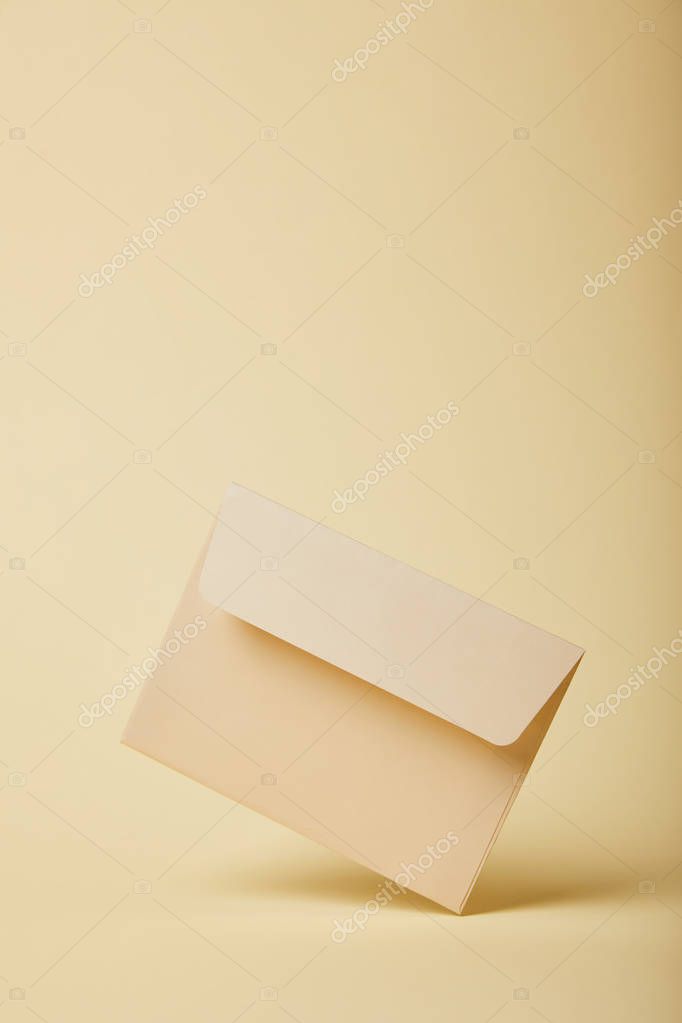 Beige and empty envelope on yellow background with copy space