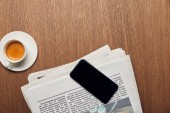 top view of newspaper near cup with coffee and smartphone with blank screen 