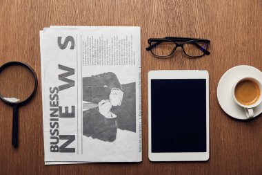 gazete, fincan kahve, boş ekran ve gözlük ile dijital tablet yakınındaki Büyüteç'in Üstten Görünüm