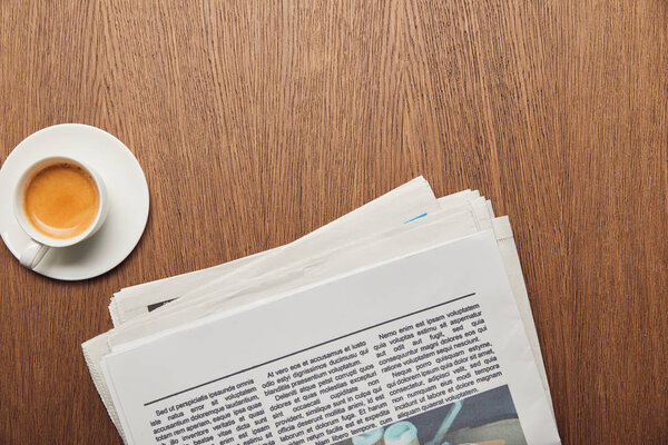 top view of newspaper near cup of coffee on wooden surface 