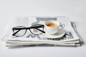 glasses near cup of coffee and business newspaper on white 