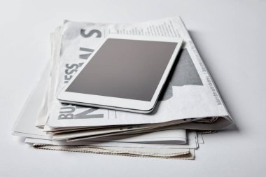 digital tablet with blank screen near business newspapers with articles on white  clipart