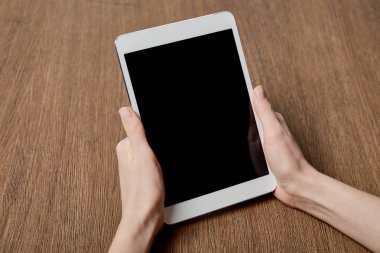 Dijital tablet ile boş perde ahşap yüzeye yakın tutan kadın görünümünü kırpılmış 