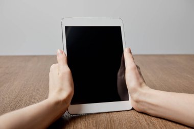 ahşap yüzeye yakın boş ekran ile dijital tablet kullanan kadın görünümünü kırpılmış 