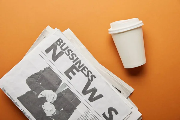 商业报纸的顶视图靠近纸杯与饮料在橙色 — 图库照片