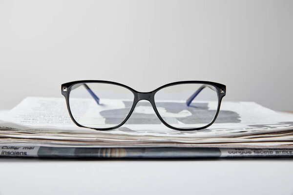 selective focus of glasses near newspaper on white 