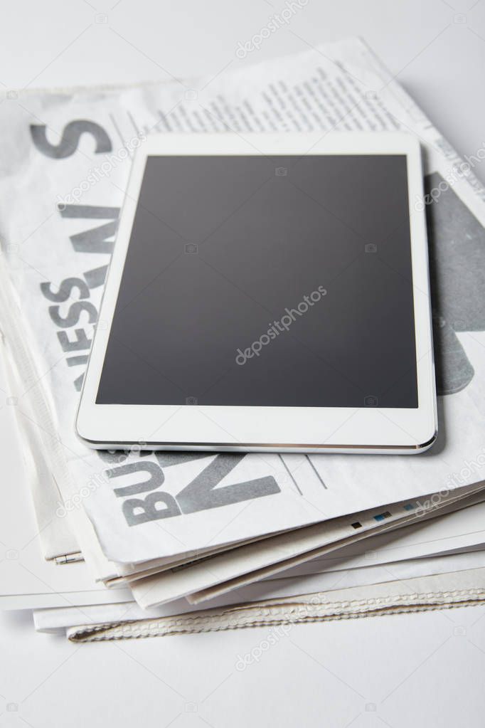 digital tablet with blank screen on business newspapers on white 