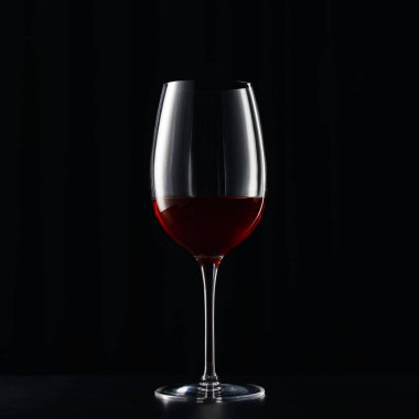 Glass of red wine on dark surface isolated on black clipart