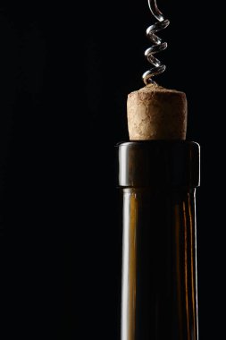 Glass wine bottle with wooden cork and corkscrew isolated on black clipart