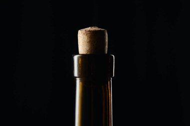 Close up view of glass wine bottle with wooden cork isolated on black clipart