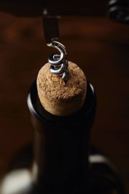 Wine bottle with wooden cork and corkscrew on brown clipart