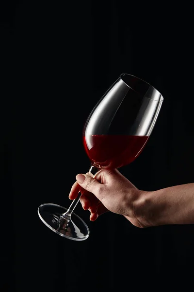 Cropped view of woman holding wine glass with red wine isolated on black