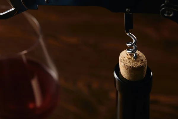 Bottle with wooden cork and steel corkscrew on brown