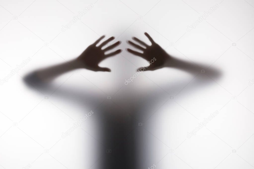 Blurry silhouette of person touching glass with hands