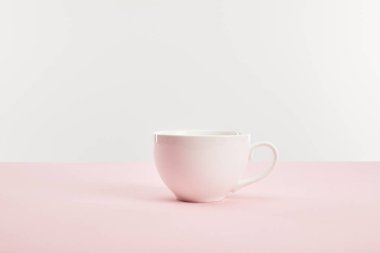 white cup with drink on pink surface isolated on grey  clipart