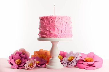 pembe doğum günü pastası kek stand üzerinde beyaz izole kağıt çiçekler yakınındaki mum ile