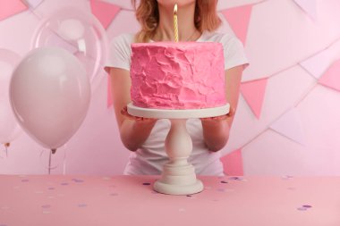 lezzetli pembe doğum günü pastası kek kürsüye mum yanan ile yakın duran kadın kırpılmış görünümünü 