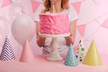 tatlı pembe doğum günü pastası kek kürsüye mum yanan ile yakın duran kadın kırpılmış görünümünü 