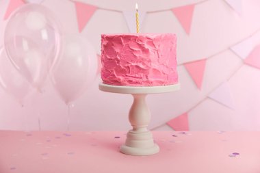 pasta stand yakın hava balonları ve dekorasyon mum yanan ile lezzetli pembe doğum günü pastası