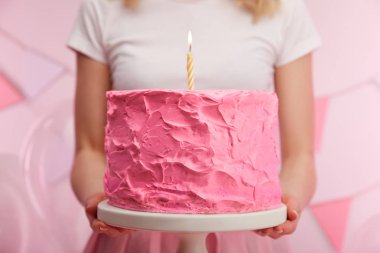 kek standı tatlı pembe doğum günü pastası ve yanan mum tutan kadının yakın çekim 