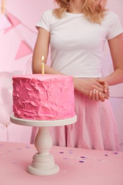 kırpılan pişmiş lezzetli doğum günü pastası kek kürsüye mum yanan ile yakın duran kadın görünümünü 