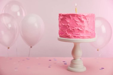 pasta stand yakın hava balonları ve dekorasyon pembe üzerinde mum yanan ile tatlı ve lezzetli doğum günü pastası