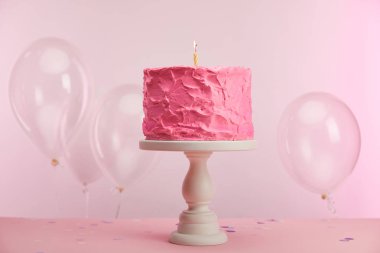 pasta stand yakınındaki hava balonları pembe üzerinde mum yanan ile tatlı ve lezzetli doğum günü pastası