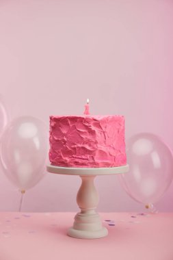 pembe ve lezzetli doğum günü pastası kek stand yakınındaki hava balonları pembe üzerinde yanan bir mum 