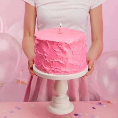 lezzetli pembe doğum günü pastası kek standı holding ve hava balonları yakınındaki bir numaralı mum yanan kadın kırpılmış görünümü