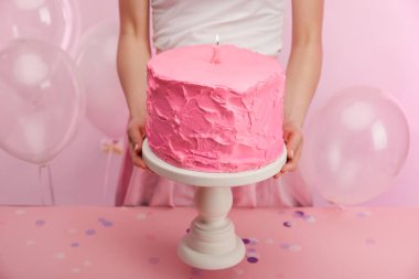 pembe tatlı doğum günü pastası kek standı holding ve hava balonları yakınındaki bir numaralı mum yanan kadın kırpılmış görünümü