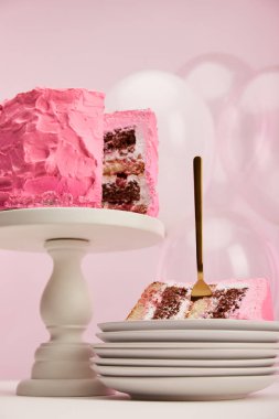 lezzetli doğum günü pastası hava balonları pembe üzerinde yakınındaki beyaz daire içinde altın çatal ile parçasının alttan görünüm 