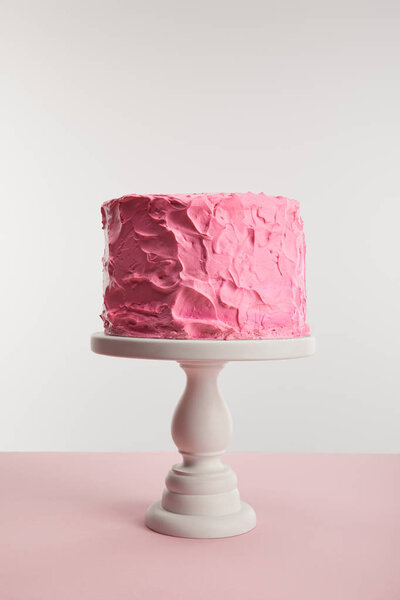 sweet pink birthday cake on cake stand isolated on grey