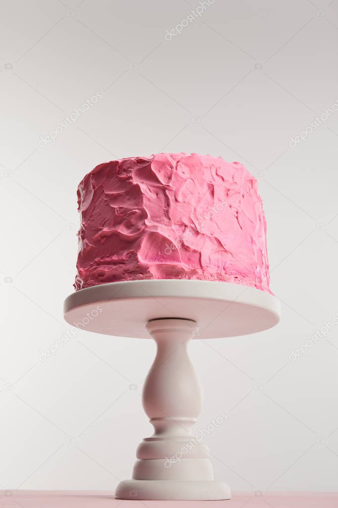 bottom view of pink birthday cake on cake stand on grey