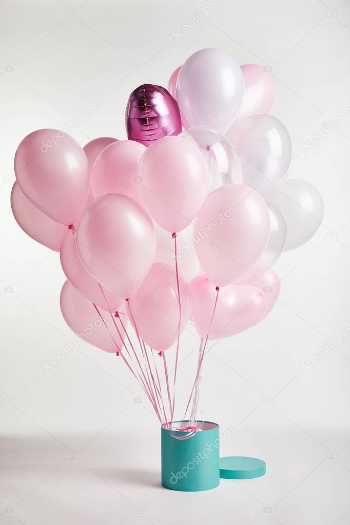 bundle of decorative pink balloons with turquoise gift box on white