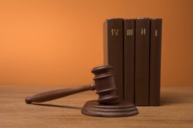 selective focus of volumes of brown books in leather covers and gavel on wooden table  clipart