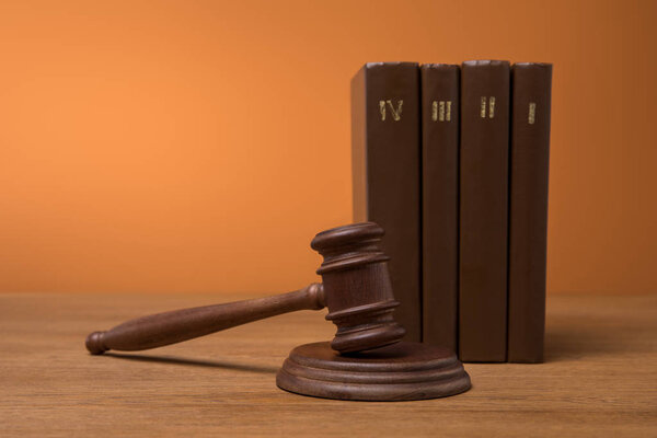 selective focus of volumes of brown books in leather covers and gavel on wooden table 