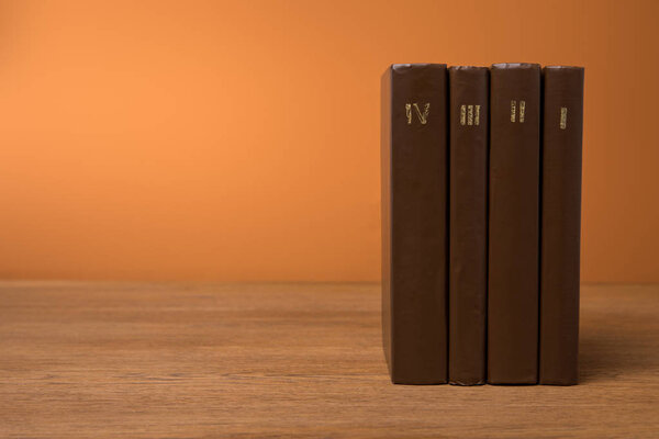 volumes of vintage books in leather brown covers on wooden table 
