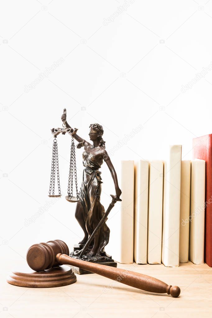 metal figure with scales of justice, gavel and books on wooden table isolated on white