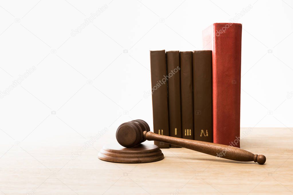 wooden gavel and row of books on wooden table isolated on white