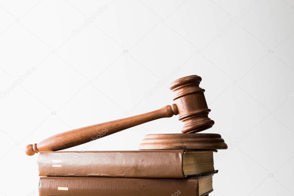 wooden gavel on pile of brown books isolated on white