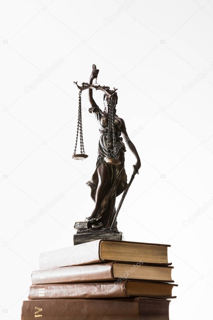 low angle view of bronze figurine with scales of justice on pile of brown books isolated on white