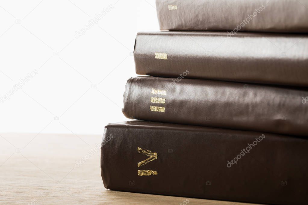 volumes of old books in leather brown covers on wooden table isolated on white