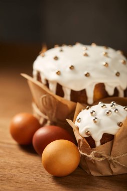 seçici odak sprinkles ve boyalı tavuk yumurtası ahşap yüzeyi ile lezzetli Paskalya kek