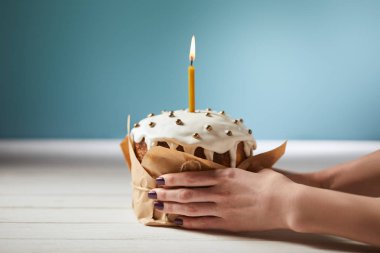 Paskalya kek tutan kadın kırpılmış görünümünü sprinkles ve turkuaz üzerinde yanan muma süslenmiş