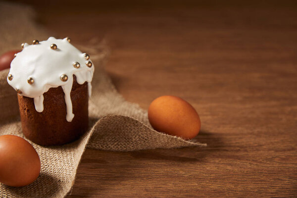 decorated easter cake and painted chicken eggs on wooden surface with copy space